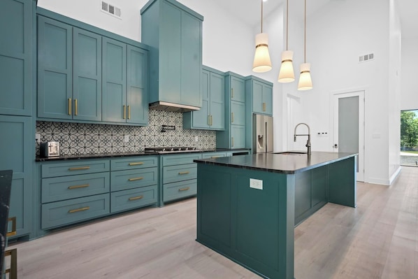 Une cuisine moderne avec des meubles de couleur turquoise, un pare-feu décoré et un îlot central.