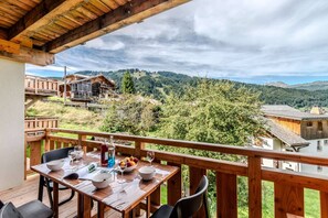 A wooden deck with a table set for dining, overlooking a mountainous landscape. - Charming Apartment – Ideal for skiing and MTB (MORZINE)