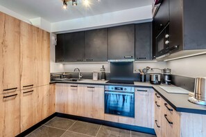 A modern kitchen with wooden cabinets, a built-in oven, and stainless steel appliances. - Charming Apartment – Ideal for skiing and MTB (MORZINE)