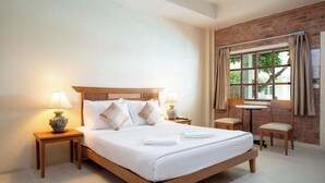 Una camera d'albergo con un letto in legno, due comodini con lampade, un tavolino rotondo e una sedia.