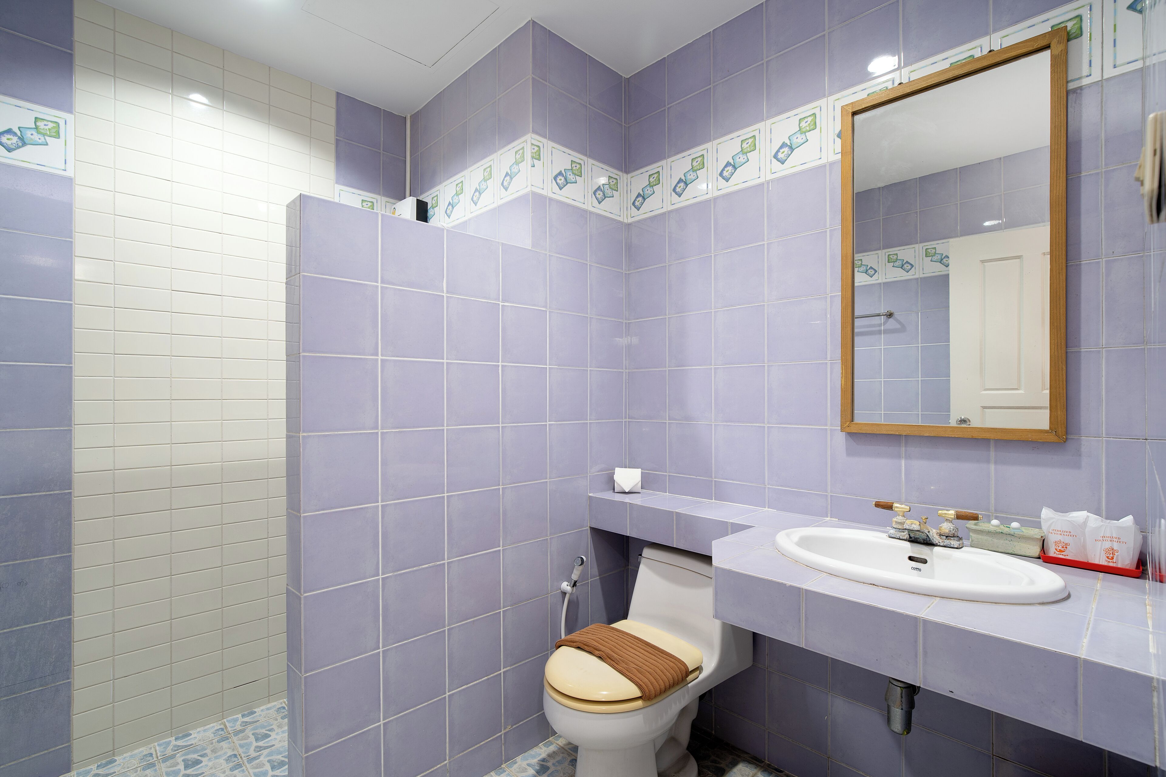 A bathroom with purple tiles, a white sink, and a mirror.