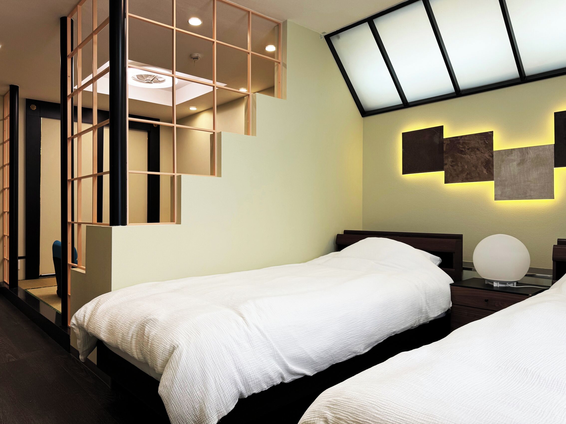 Habitación de hotel con dos camas, diseño moderno y tragaluz.