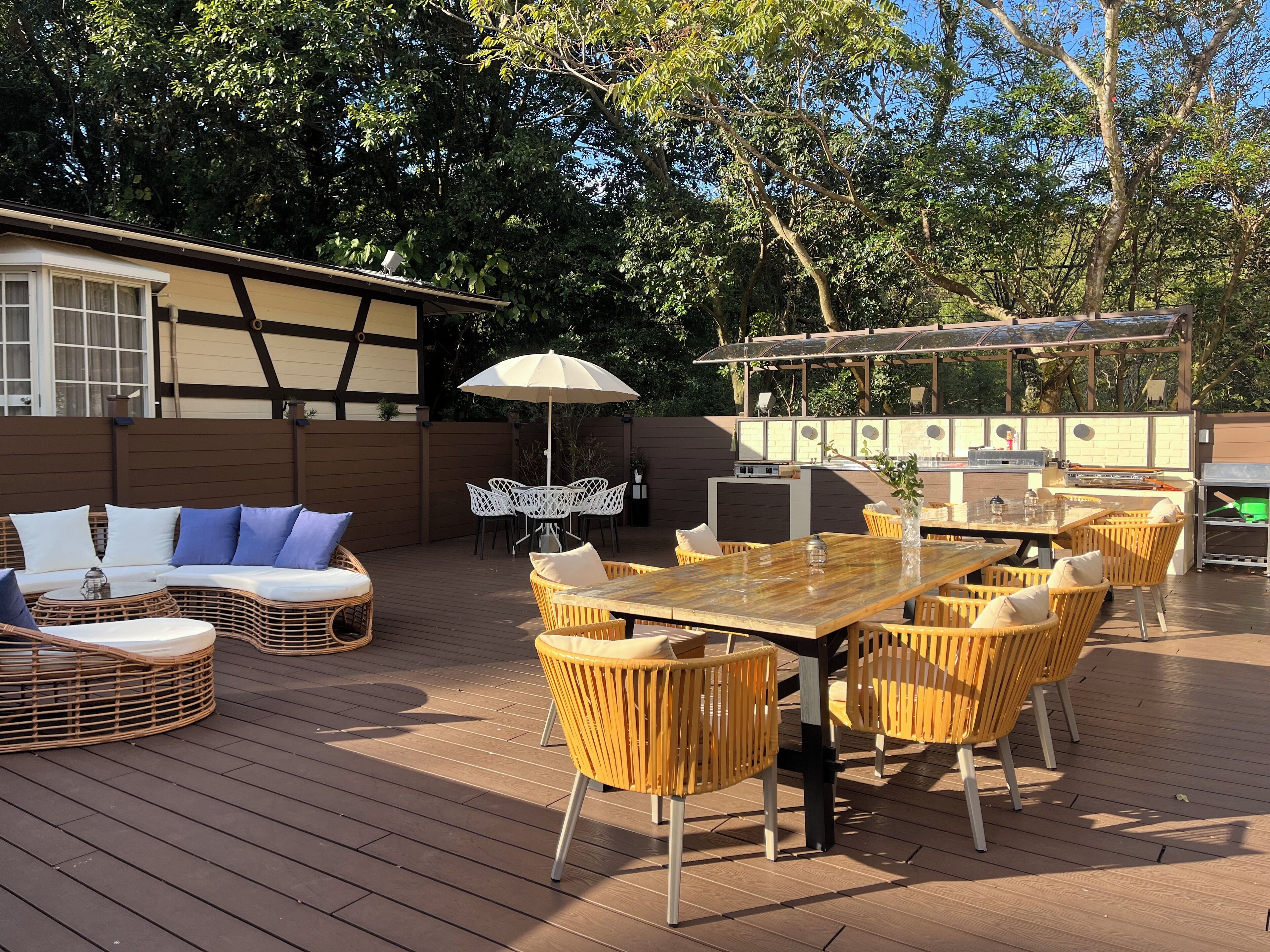 Une terrasse extérieure aménagée avec des meubles en osier, une table en bois et un espace barbecue.