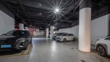 Un garaje para estacionamiento con varios automóviles, pilares de hormigón e iluminación superior.