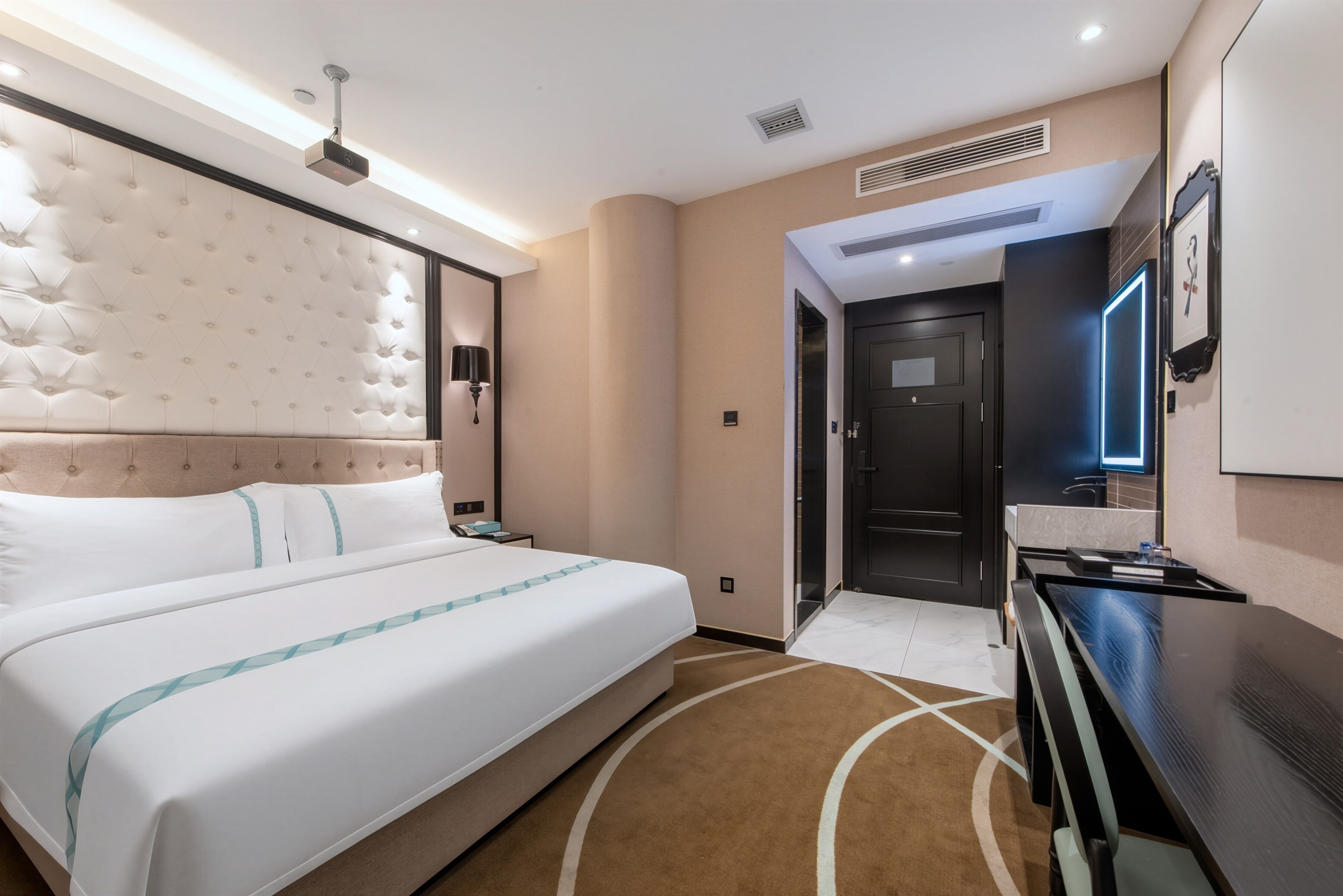 A hotel room with a large bed, a desk, a television, and a door leading to a bathroom.