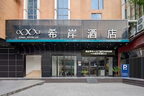 L’entrée d’un hôtel, avec une enseigne indiquant « XANA HOTELLE » et un panneau de signalisation indiquant la direction du parking.
