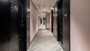 A hotel corridor with black doors, a tiled floor, and a ceiling with recessed lighting. - Pazhou XANA Deluxe International Hotel Pazhou Convention and Exhibition Center Changgang Subway Metro Branch - Free Shuttle Bus to Canton Fair Complex During Canton Fair Period (Guangzhou)