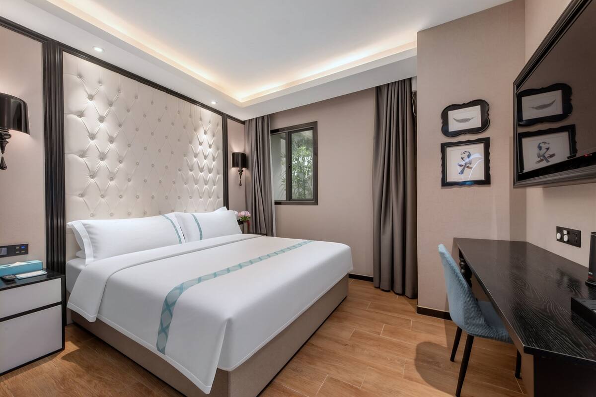 A modern hotel room with a large bed, a desk, and a window.