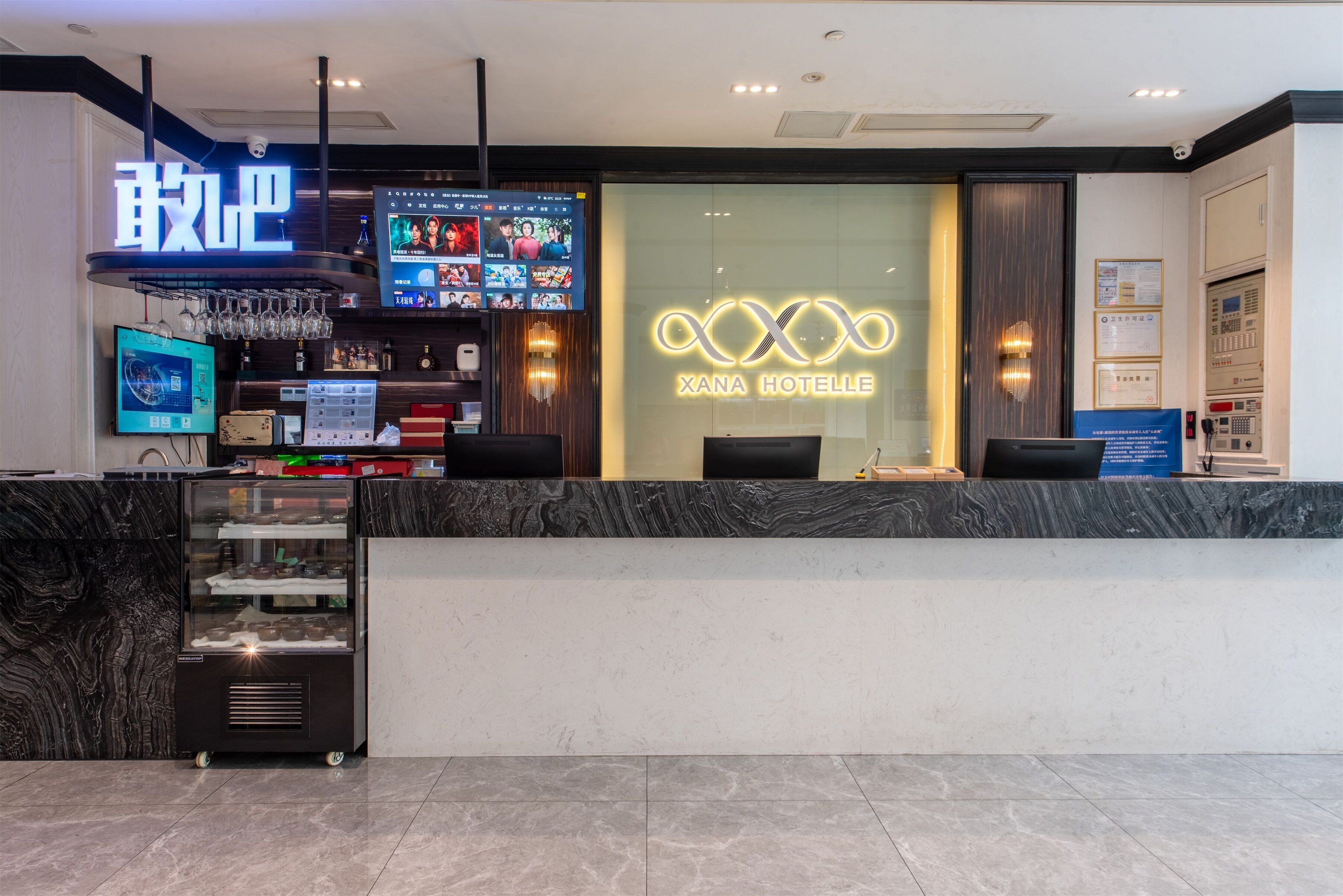 A hotel reception area with a digital screen displaying content, a glass display case with items, and a reception desk.