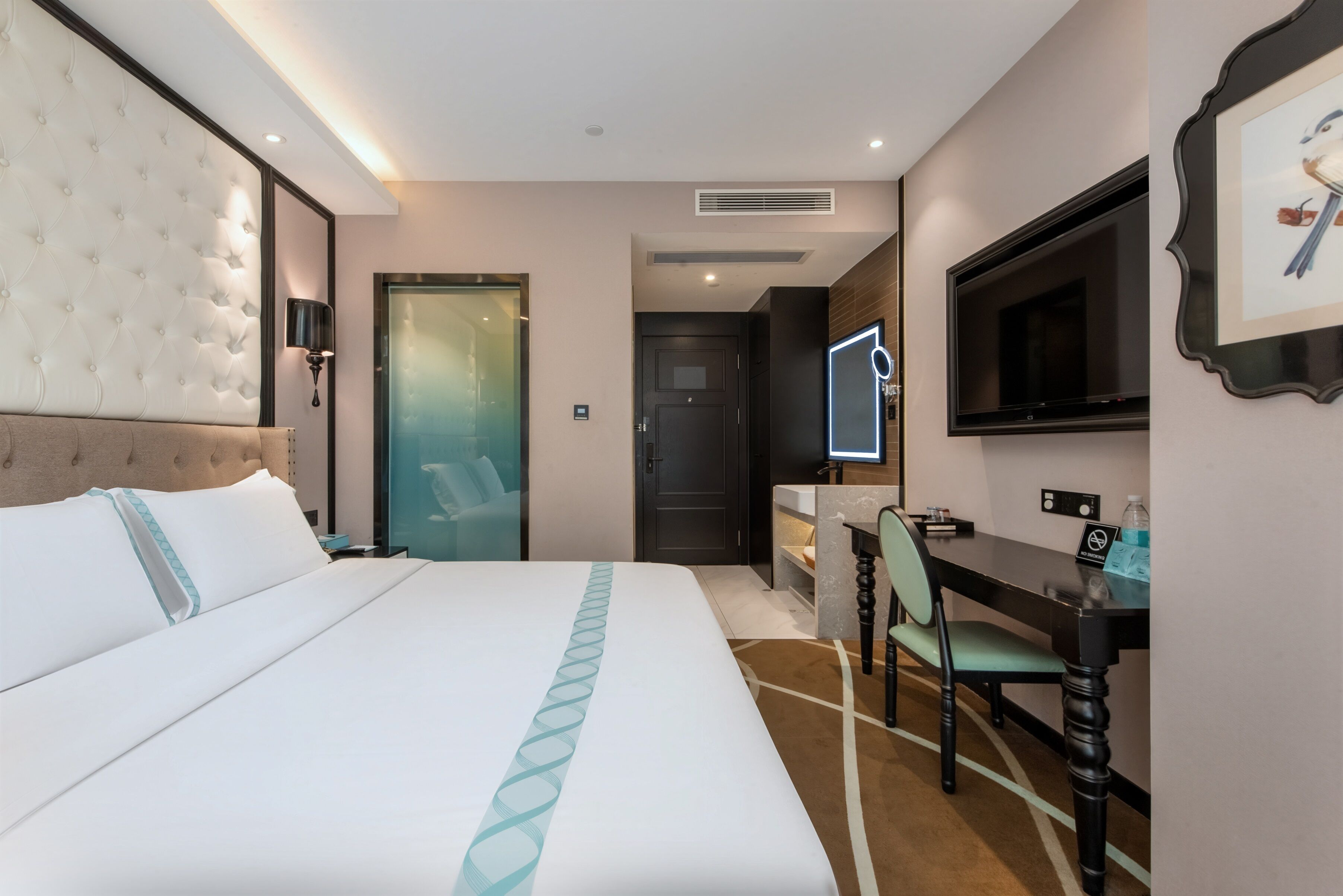 Une chambre d’hôtel avec un grand lit, un bureau, une chaise, une télévision et un tableau encadré au mur.