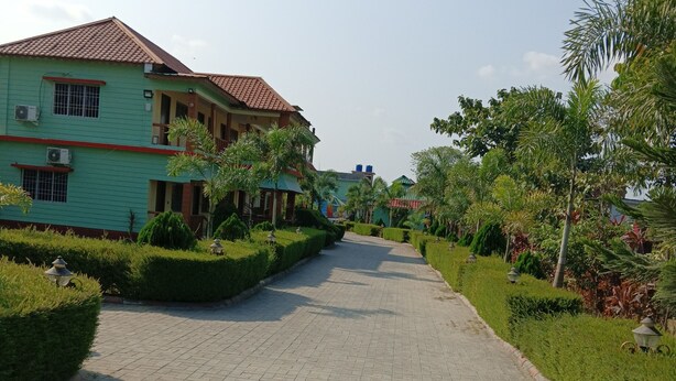 A paved pathway leading to a building with a tiled roof and multiple windows. - RESORT RUPKATHA (Mal)