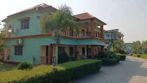 A two-story building with a balcony, air conditioning units, and a well-maintained garden with a pathway. - RESORT RUPKATHA (Mal)