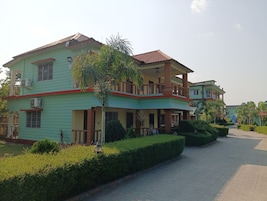 A two-story building with a balcony, air conditioning units, and a well-maintained garden with a pathway.