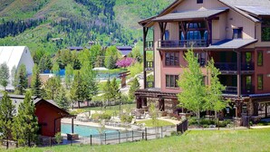 Un hôtel à plusieurs étages doté d’une piscine, entouré de verdure et de montagnes.