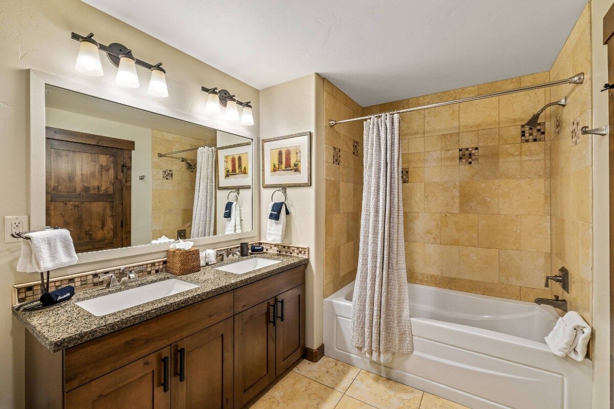 A bathroom with two sinks, a large mirror, and a bathtub.