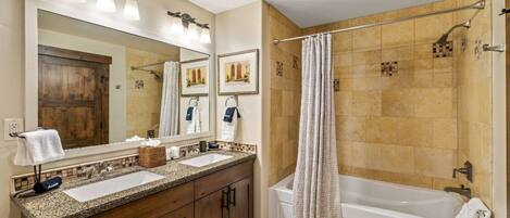 A bathroom with two sinks, a large mirror, and a bathtub.