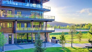 Un immeuble à plusieurs étages doté d’une façade en verre, d’une terrasse et offrant une vue sur un paysage verdoyant.