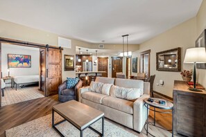 A spacious living room with a sofa, a coffee table, and a dining area in the background.
