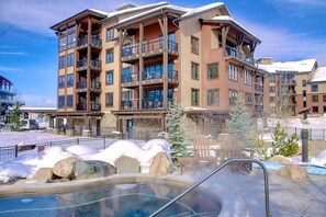 A multi-story hotel with balconies, a pool area, and snow-covered landscape.