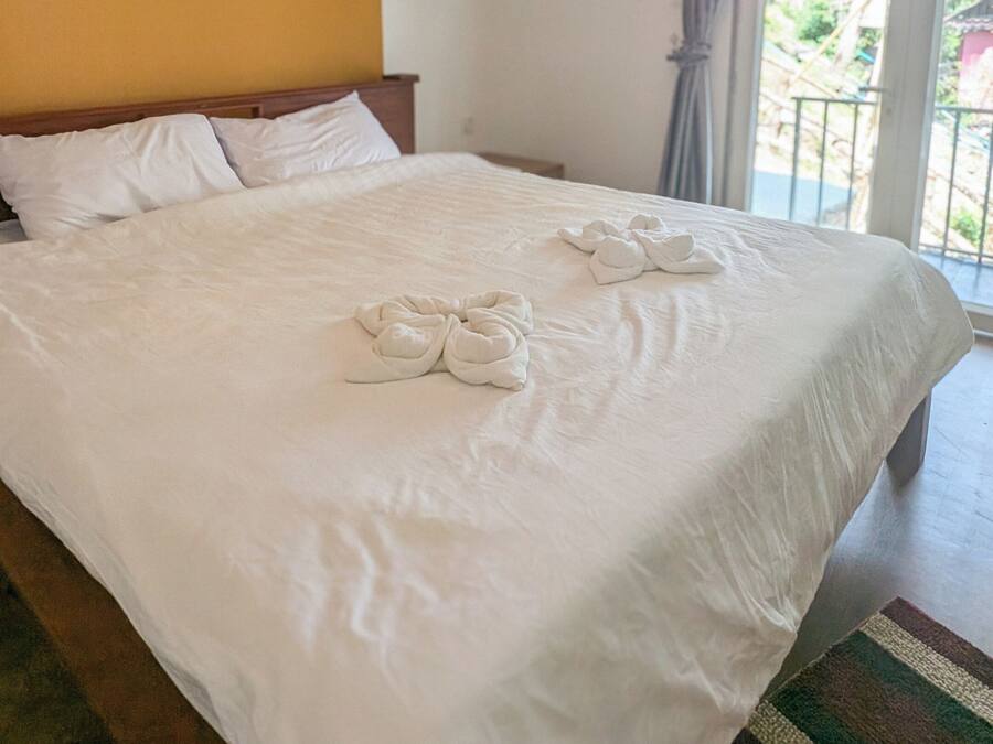 Habitación de hotel con una cama grande, dos lámparas colgantes, una ventana con cortinas y vistas al exterior.