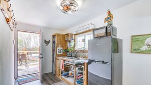 Eine kleine Küche mit integriertem Kühlschrank, Holzschränken und einem Fenster mit Blick auf eine Terrasse.