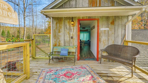Eine rustikale Holzhütte mit einer Veranda, einer Bank und einem Teppich. Ein Schild mit der Aufschrift "The Porch".