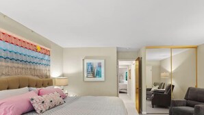 Una habitación de hotel con cama, una silla, un escritorio y un espejo grande.
