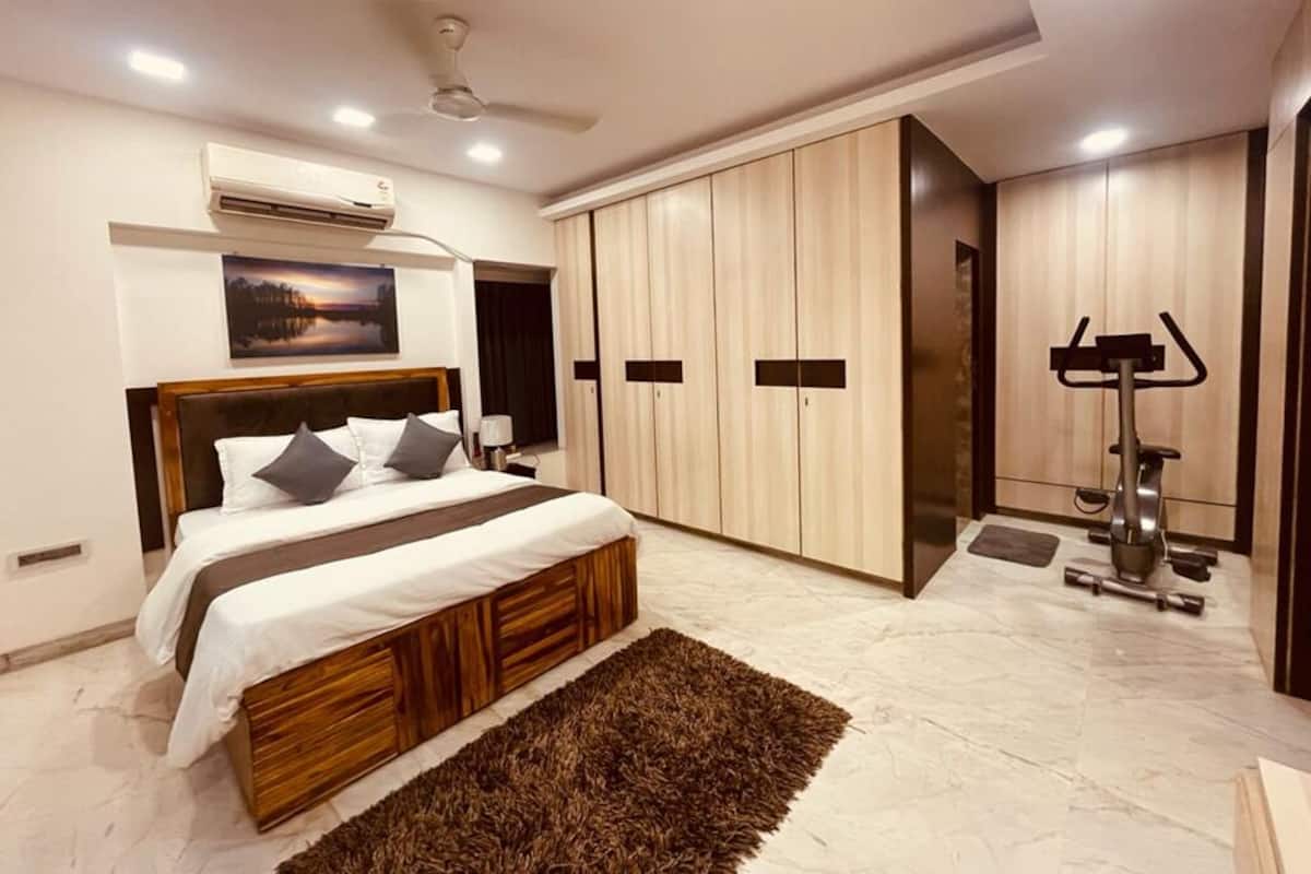 Ein modernes Schlafzimmer mit Bett, Kleiderschrank und Fitnessgeräten.