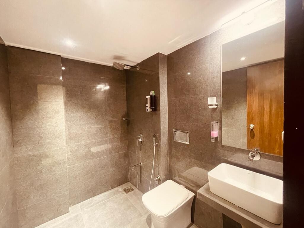 Un baño moderno con ducha a nivel, inodoro y lavamanos.