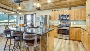 Une cuisine dotée de meubles en bois, d’appareils électroménagers en acier inoxydable et d’un îlot central avec des tabourets de bar.