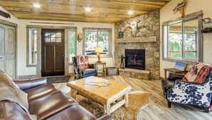 Un intérieur rustique avec une cheminée en pierre, des meubles en cuir et un plafond en bois.