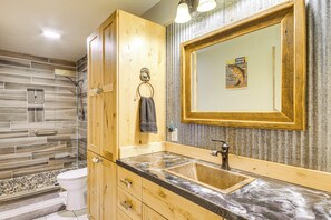 Un baño con tocador de madera, lavabo y espejo.