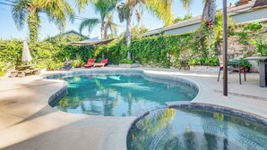 Una piscina dalla forma sinuosa, circondata da un patio con sedie rosse e un tavolo.