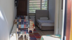 A small, cozy room with a bed, a table, and a window with blinds. - Sahil evim pansiyon (Ünye)