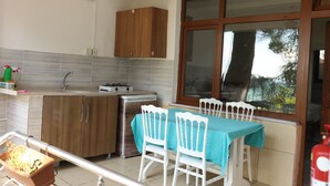 A kitchen with wooden cabinets, a gas stove, and a window with a view of trees. - Sahil evim pansiyon (Ünye)