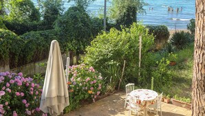 A patio with a table and chairs, surrounded by lush greenery and a view of the sea. - Sahil evim pansiyon (Ünye)