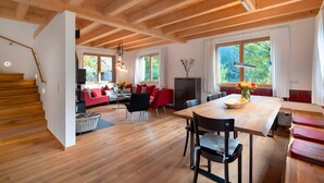 A spacious living area with a wooden ceiling, a dining table, and a sofa set.