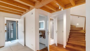 A modern interior with wooden beams, a staircase, and a bathroom with a mirror.