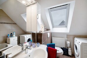 Une salle de bain moderne avec un puits de lumière, un lave-linge, un évier et des toilettes.