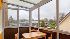 A corner room with a table and chairs, large windows, and a view of the outside.