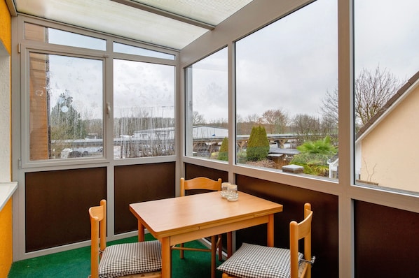 Habitación de esquina con una mesa y sillas, ventanas amplias y vistas al exterior.