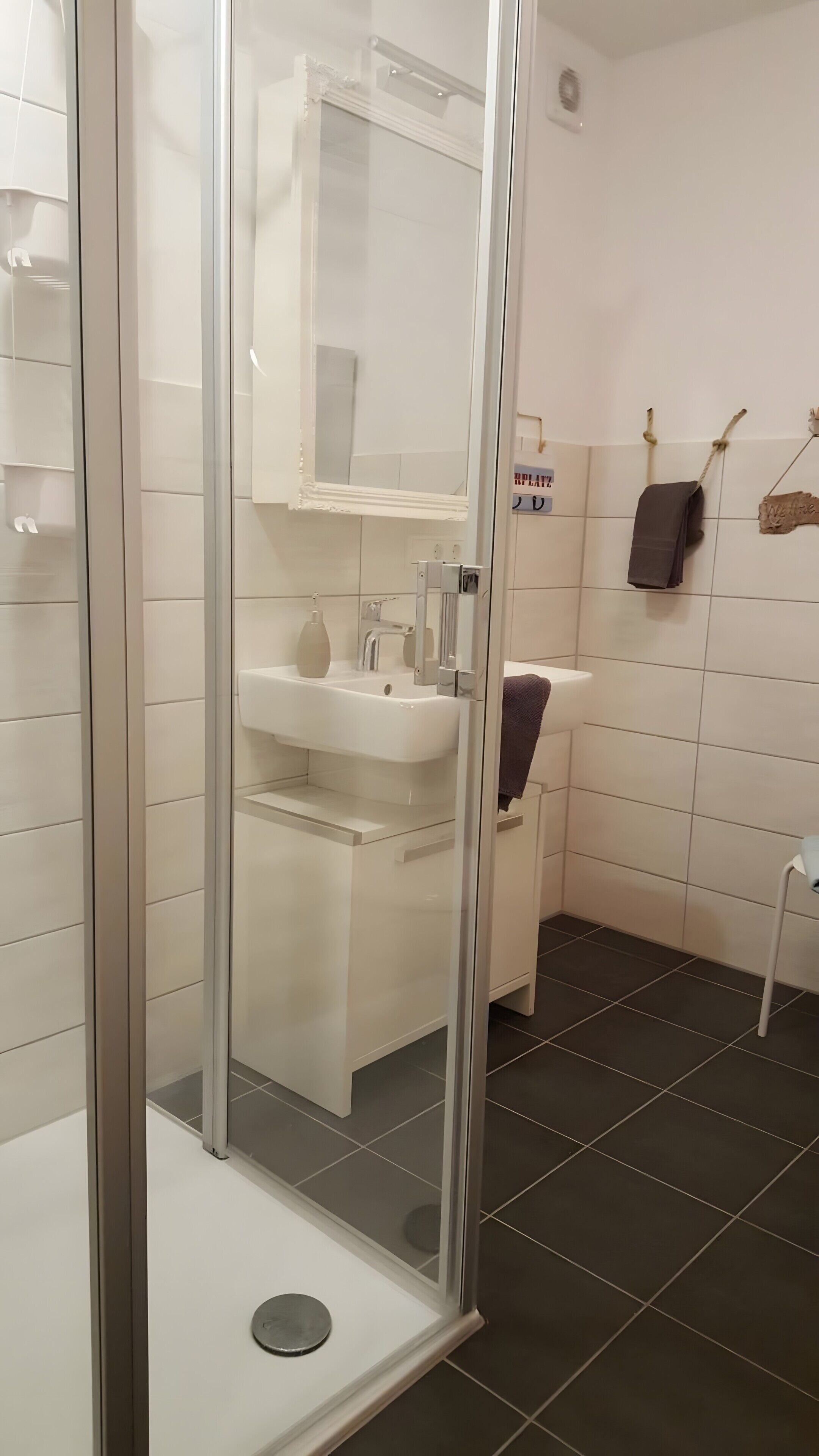 Un baño moderno con cabina de ducha de vidrio, un lavabo blanco y un espejo encima.