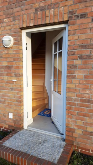 A brick building with a white door leading to a wooden staircase.