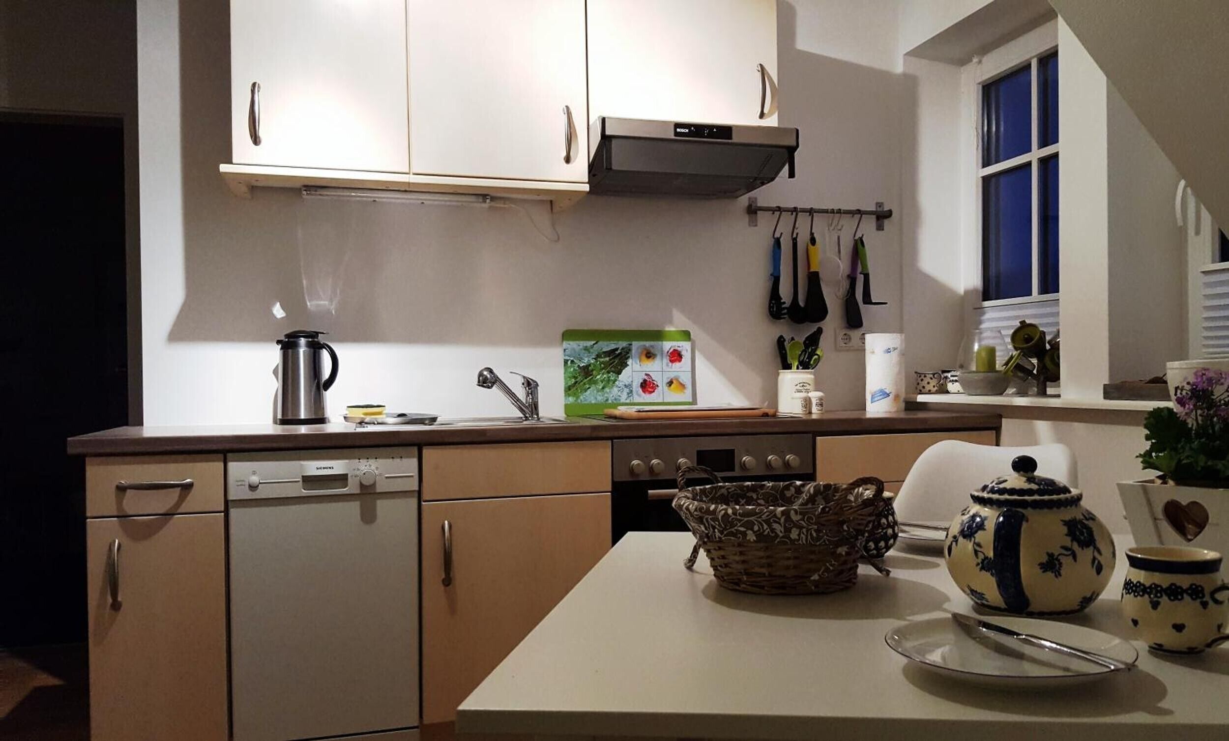 Une cuisine équipée d’un lave-vaisselle, d’une cuisinière et de divers ustensiles de cuisine.