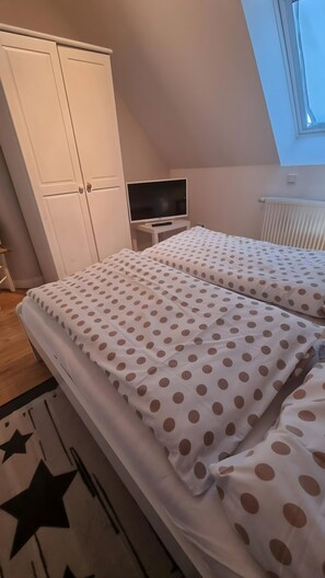 Makuuhuoneessa on kaksi sänkyä, vaatekaappi, televisio ja kattolyhty.