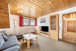 A cozy room with a wooden ceiling, a sofa, a TV, and a small table. - Apartment 'Abendsonne' with Mountain View, Shared Terrace and Wi-Fi (Todtnau)