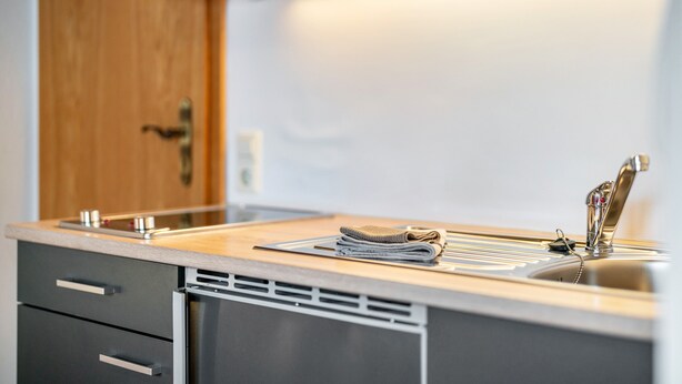 A modern kitchen with a sink, a towel, and a wooden door. - Apartment 'Einzelzimmer' with Mountain View, Shared Terrace and Wi-Fi (Todtnau)