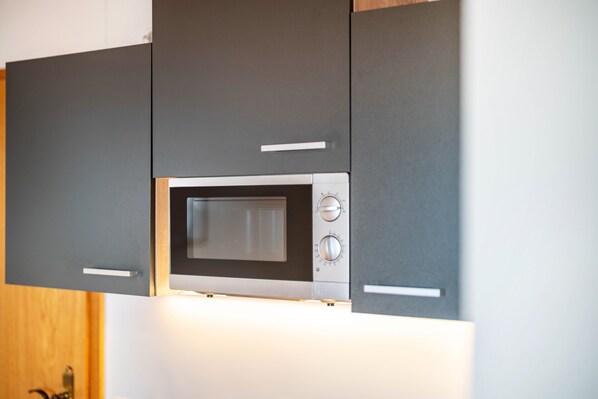 A modern kitchen with a built-in microwave, stainless steel appliances, and dark cabinetry.