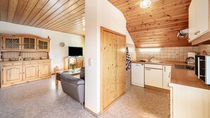 Une cuisine avec des meubles en bois, un coin repas avec un canapé et un téléviseur.
