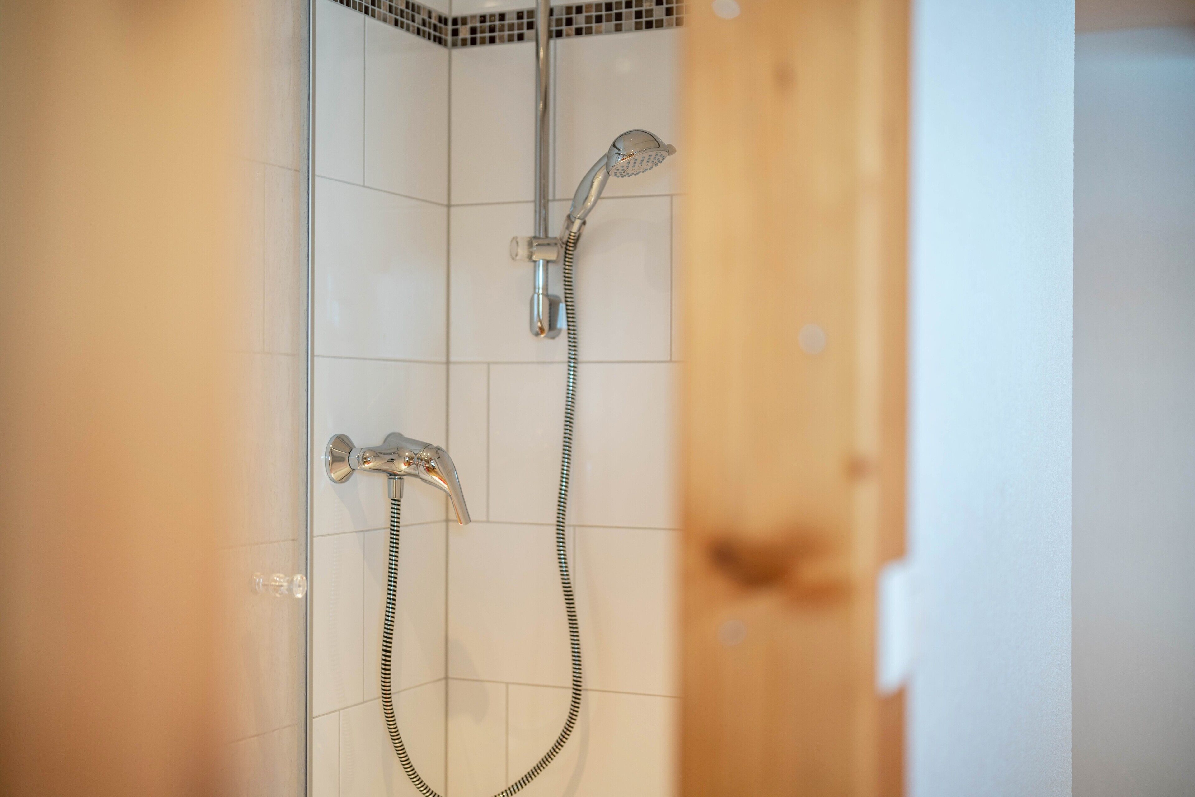 Eine Dusche mit Handbrause und wandmontiertem Wasserhahn.
